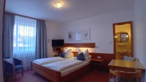 a bedroom with a bed and a table and a mirror at Gasthaus Krone in Randersacker