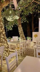 a table with white chairs and a tree with lights at Paris Studios & Apartment in Agia Paraskevi