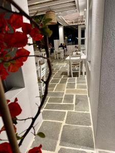 a hallway with red flowers and tables in a restaurant at Paris Studios & Apartment in Agia Paraskevi