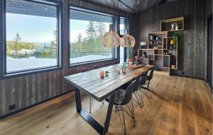 a dining room with a wooden table and two windows at Awesome Home In Rjukan With Sauna in Rjukan