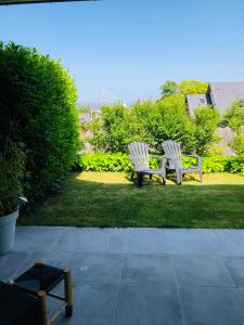 Dos bancos sentados en el césped de un patio. en Bel Air Studios-Terrasse couverte-Jardinet-Vue Pont de Normandie-Parking privé, en Honfleur