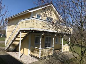 a small yellow house with a porch and stairs at Ferienwohnung im Ferienresort Kulkwitzer See Leipzig in Leipzig +7 photos