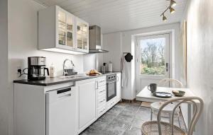 a kitchen with white cabinets and a table and a window at 2 Bedroom Nice Apartment In Aakirkeby in Åkirkeby