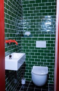 a green tiled bathroom with a sink and a toilet at Hotel Kouty - Lesní Apartmány in Ledeč nad Sázavou