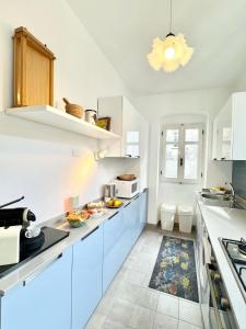 a white kitchen with blue cabinets and a chandelier at Casa delle volte in Finale Ligure +28 photos