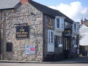 un viejo edificio de piedra con un cartel. en The Dolphin Tavern, en Penzance