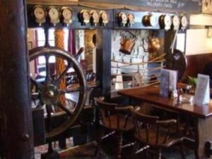 een kamer met een houten tafel en een stuurwiel bij The Dolphin Tavern in Penzance