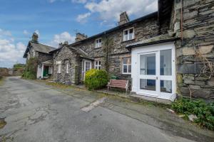 an old stone house with a bench in front of it at Rose Bank Cottage Coniston in Coniston