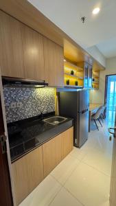a kitchen with wooden cabinets and a stainless steel refrigerator at Apartemen Roseville at BSD by Kenkei in Dadap