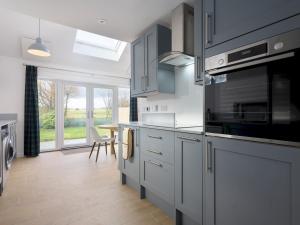 a kitchen with gray cabinets and a large window at Golfers Haven Links Cottage Crail - Pass the Keys in Crail