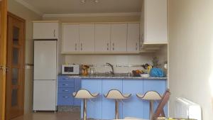 a kitchen with blue and white cabinets and stools at Mirador do Xistral in Valle de Oro