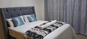 a bed with white sheets and blue pillows at Twinex Accommodation Bellville in Stikland +14 photos