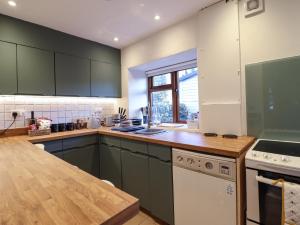 una cucina con armadi verdi e piano di lavoro in legno di Gwynfa a Betws-y-coed