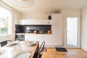 a kitchen with white cabinets and a table with chairs at Evasion Bretonne a Guingamp pour 12 personnes in Guingamp