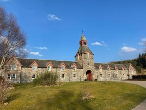 a large stone building with a tower on a grass field at Courtyard Cottage - sleeps 4 with en-suite in Tomich +13 photos