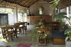 a restaurant with wooden tables and chairs and plants at Avalon in Weligama