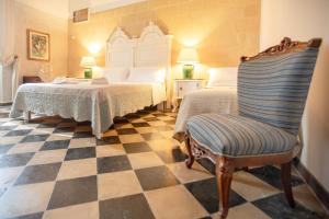 a bedroom with two beds and a chair and a checkerboard floor at VILLA LA TONNARA in Punta Prosciutto