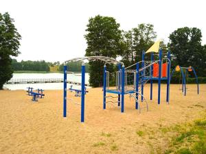 a playground in the sand near a body of water at Domki na Łące in Ostrów Pieckowski