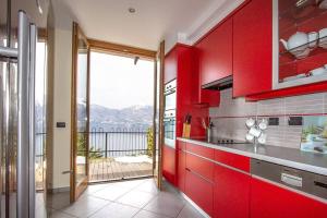 a kitchen with red cabinets and a balcony at Sopra il Lago 112 in Brezzo