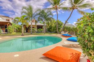 a swimming pool with palm trees and a house at LES PECHEURS DU LAGON in Saint-Leu