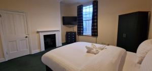 a bedroom with a bed with white sheets and a fireplace at SELF CHECK-IN QUICK ROOMz WAKEFIELD in Wakefield