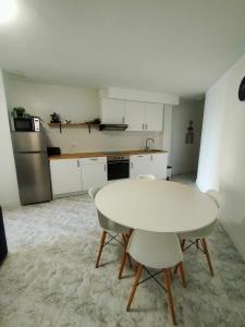 a white kitchen with a white table and chairs at Caballito de mar in Malpica +11 photos