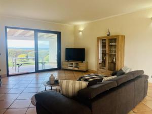 a living room with a couch and a flat screen tv at Villa esclusiva con piscina privata e vista mare in San Michele