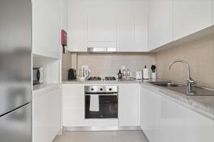 une cuisine blanche avec un évier et une cuisinière dans l'établissement Silkhaus modern 1BDR in Downtown with balcony, pool, gym, à Dubaï 10 autres photos