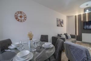 una sala da pranzo con tavolo, sedie e orologio di The Larky - Modern 2 Bed Cottage in Larkhall a Larkhall