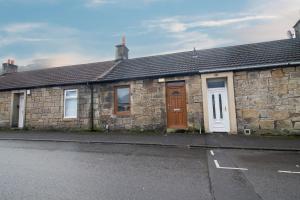 una casa in pietra con porte marroni e una strada di The Larky - Modern 2 Bed Cottage in Larkhall a Larkhall