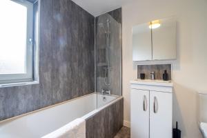 un bagno con doccia e vasca da bagno di The Larky - Modern 2 Bed Cottage in Larkhall a Larkhall Altre 17 foto