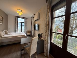 una camera con letto, scrivania e finestre di Arbostora Charme Hotel a Morcote