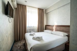 a bedroom with a bed with white sheets and a window at MILDOM Express in Almaty