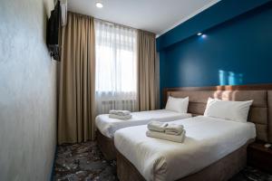 two beds in a hotel room with towels on them at MILDOM Express in Almaty