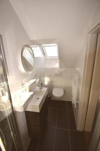 un bagno con lavandino, specchio e WC di Ferienwohnung Spitz a Dornum