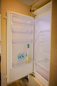 an empty refrigerator with a bottle and some drinks in it at Cozy and stylish 2 bedroom home in Leicester