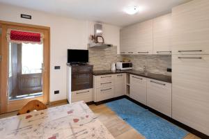 a kitchen with white cabinets and a sink and a table at Appartamento Pizalegn Bait da Rez in Livigno