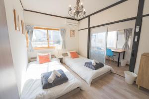 two beds in a room with a table and a desk at リトリート神戸 広々70m2 一軒家貸切 ノエビアスタジアム隣接 in Kobe
