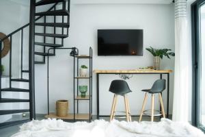 a living room with two stools and a tv on a wall at Emerald Suite Plaza in Corralejo