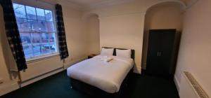 a bedroom with a white bed with a window at SELF CHECK-IN QUICK ROOMz WAKEFIELD in Wakefield