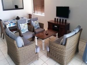 a living room with chairs and a table and a television at Cowrie Cove 5 in Ballito