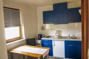 a small kitchen with blue cabinets and a table at Pension Apart in Glashütten