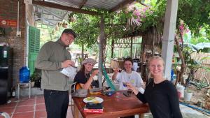 a group of people standing around a wooden table at Homestay Dat Phu in Tuy Hoa +92 photos