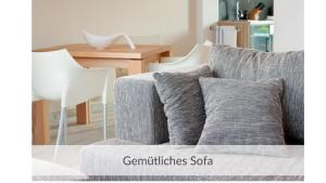 a gray couch with white chairs and a table at Strandvilla Haffkrug Apartment Strandläufer in Scharbeutz