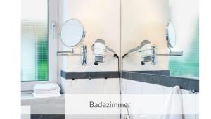a bathroom with two mirrors and a sink at Strandvilla Haffkrug Apartment Strandläufer in Scharbeutz