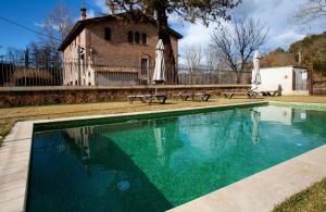 a swimming pool with two umbrellas and a house at Casa Fàbregas - Benestar Natural in Viladrau