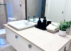 un comptoir de salle de bain avec un lavabo et un miroir dans l'établissement Terrace House with Character at Prime Location, à Sydney 8 autres photos