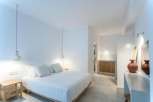 a white bedroom with a bed and a table at Paris Studios & Apartment in Agia Paraskevi