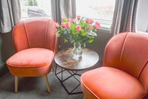 two orange chairs and a vase with flowers on a table at Smarties Guest House in Newquay