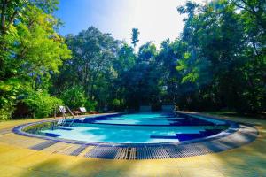 a large swimming pool with trees in the background at Jays Holiday Resort in Habarana